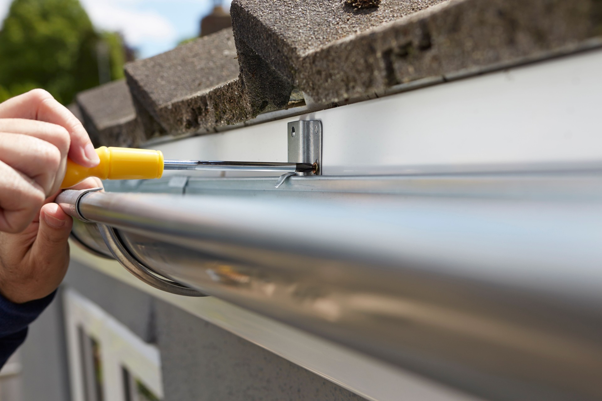 Close Up Of Man Replacing Guttering On Exterior Of House